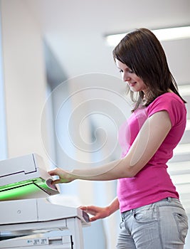 Pretty young woman using a copy machine