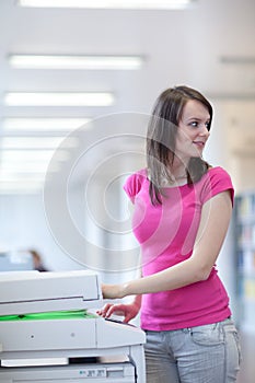 Pretty young woman using a copy machine