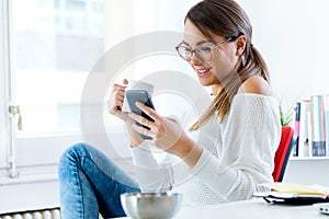 Pretty young woman using her mobile phone in the office.