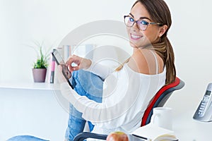 Pretty young woman using her mobile phone in the office.