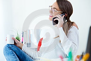 Pretty young woman using her mobile phone in the office.