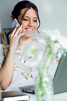 Pretty young woman using her mobile phone in the office.