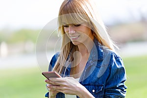 Pretty young woman using her mobile phone in the park.