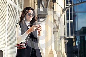 Pretty young woman using her mobile phone while standing in the street