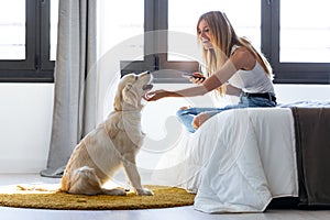 Pretty young woman using her mobile phone while staying with her dog at home