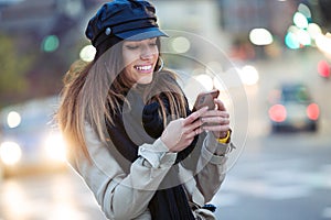 Pretty young woman using her mobile phone in the street at night