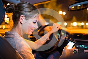 Pretty young woman using her smart phone while driving her car