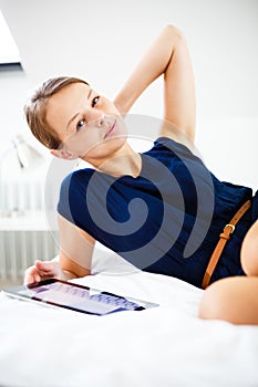 Pretty, young woman using her tablet computer in bed