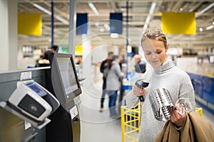 Pretty, young woman using self service checkout in a store