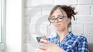 Pretty young woman using smartphone smiling happy indoors. Girl sms texting using app on smart phone at home.