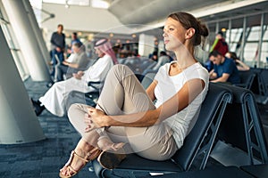 Pretty, young woman waiting at a gate area of a modern airport