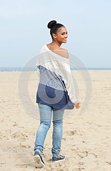 Pretty young woman walking on the beach and looking over shoulder