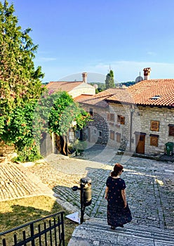 A pretty young woman walking down a beautiful classic narrow cobblestone European street with colourful flowers