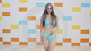 Pretty young woman walking on a poolside at indoor swimming pool. Swimming pool, water park, swimsuit