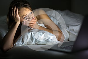 Pretty young woman watching something awful/sad on her laptop photo