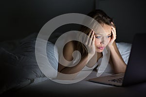 Pretty young woman watching something awful/sad on her laptop photo