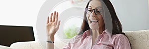 Pretty young woman wave hello show gesture online on laptop