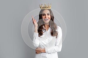 Pretty young woman wear crown,  on gray background. Girl with golden crown, arrogance and privileged status