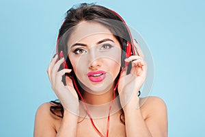 Pretty young woman wearing headphones over blue background