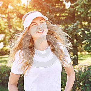 Pretty young woman wearing tennis hat. White t-shirt. Female sport player