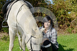 Pretty young woman with white horse riding