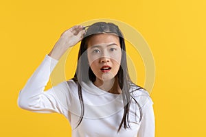 Pretty young woman in white shirt casual look posing amazement face and lifting eyeglasses to take a look closely  on yellow