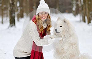 Pretty Young Woman in Winter Forest Walking with her Dog White Samoyed