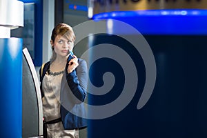 Pretty, young woman withdrawing money from her credit card