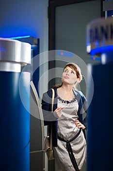 Pretty, young woman withdrawing money from her credit card