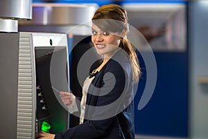 Pretty, young woman withdrawing money from her credit card
