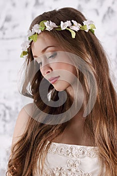 Pretty young woman in wreath with long hair looks down