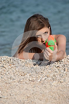 Pretty young women playing with water gun at the beach