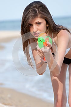 Pretty young women playing with water gun at the beach