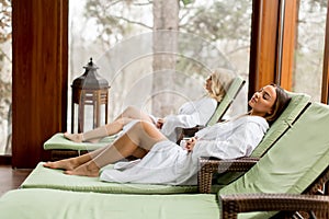 Pretty young women relaxing on the deckchair by the swimming poo