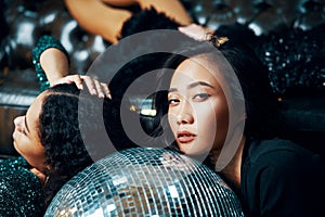 Pretyy women relax and lying down on the floor on disco ball in nightclub after crazy party