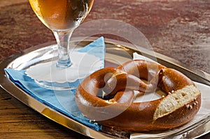 Pretzel and beer glass on blue and white serviettes