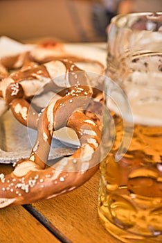 Pretzel Brezeln with Sea Salt and Glass of Beer on Rustic Wooden Table