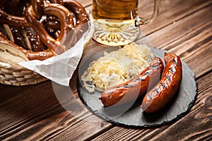 Pretzels, bratwurst and sauerkraut on wooden table