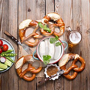 Pretzels, white bavarian sausages and beer on wooden background, german traditional food, oktoberfest