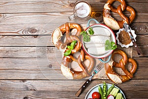 Pretzels, white bavarian sausages and vegetables on wooden background, german traditional food, oktoberfest