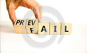 Prevail or fail symbol. Concept words Prevail or Fail on wooden cubes. Businessman hand. Beautiful white table white background.