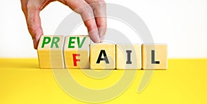 Prevail or fail symbol. Concept words Prevail or Fail on wooden cubes. Businessman hand. Beautiful yellow table white background.