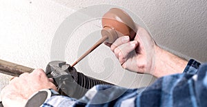 Preventative maintenance is being done by a handyman on the spring of a garage door