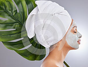 Preventing breakouts one mask at a time. an attractive young woman wearing a face mask and posing with a monstera leaf