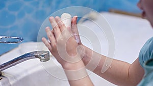 Preventing the covid-19 coronavirus pandemic, a little girl washes her hands with soap and a sanitizer