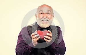 Preventing heart attack. Senior bald head bearded man holding red toy heart in hands. Mature man with valentines heart