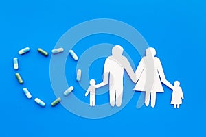 Prevention of diseases. Medicine for family health. Color pills near silhouette of family on blue background top view
