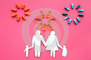 Prevention of diseases. Medicine for family health. Color pills near silhouette of family on pink background top view