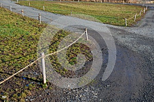 Prevention of entry to grassy areas by means of wooden poles with jute ropes edges at the sidewalk or rural gravel roads. off-road