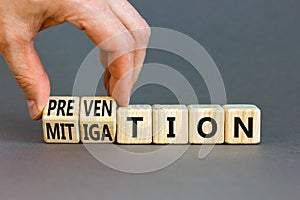Prevention or mitigation symbol. Businessman turns cubes and changes the concept word Mitigation to Prevention. Beautiful grey